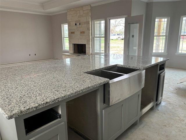 kitchen with open floor plan, a stone fireplace, ornamental molding, and light stone countertops