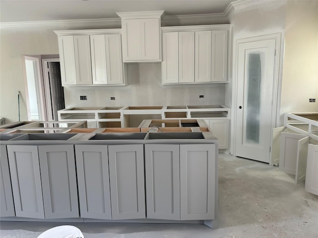 kitchen featuring concrete floors, white cabinetry, and crown molding