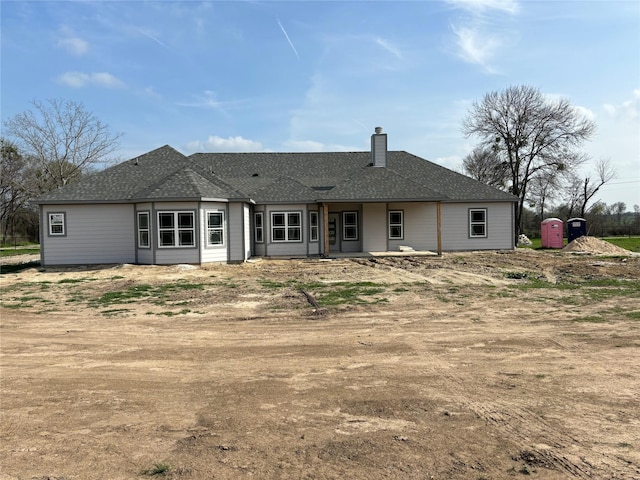 rear view of house with a shingled roof and a chimney