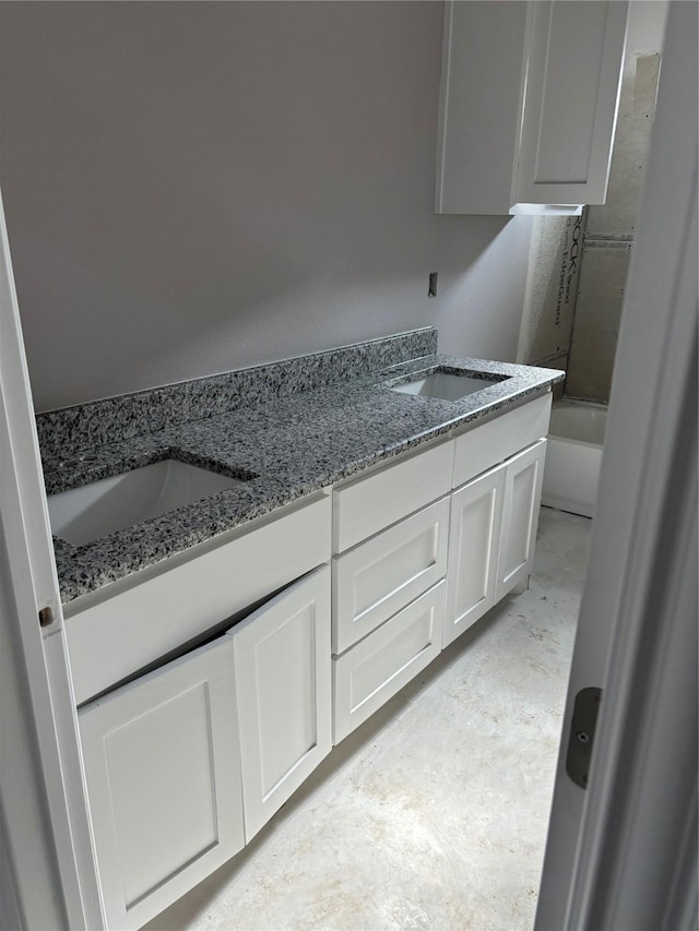 full bath with double vanity, a washtub, concrete flooring, and a sink