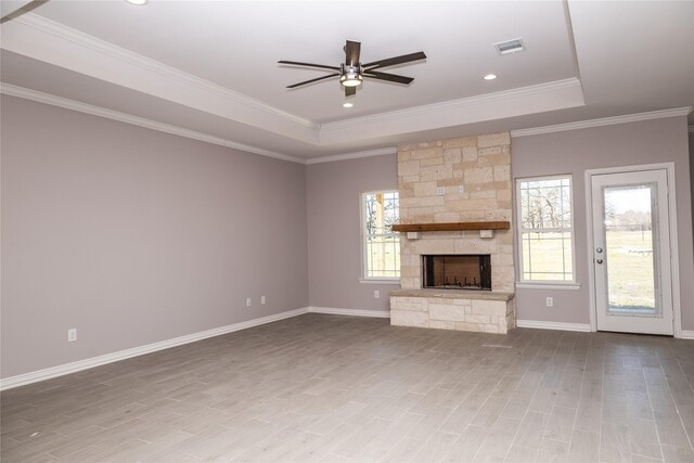 unfurnished living room with wood finished floors, a fireplace, a raised ceiling, and a wealth of natural light