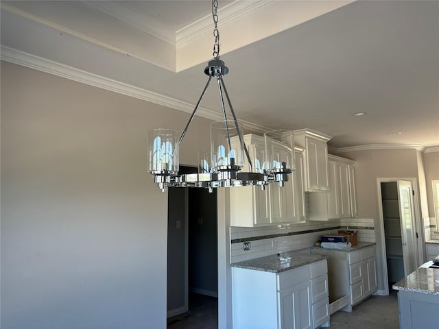 kitchen featuring white cabinetry, light stone countertops, tasteful backsplash, and ornamental molding