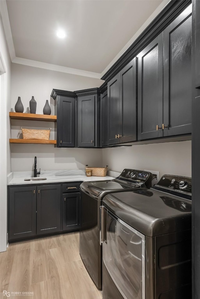 642 Caledonia Dr, Bossier City, LA 71111 - washroom featuring washing machine and dryer, a sink, light wood finished floors, ornamental molding, and cabinet space