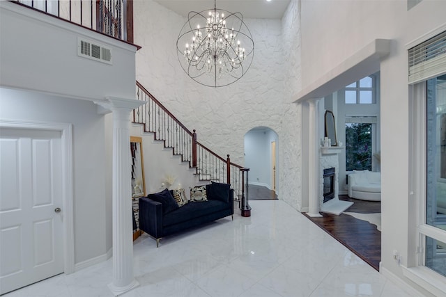 foyer featuring a towering ceiling, marble finish floor, stairway, and visible vents