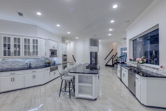 kitchen with decorative backsplash, a kitchen bar, white cabinetry, appliances with stainless steel finishes, and sink