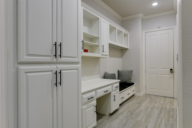 mudroom featuring light hardwood / wood-style floors, built in desk, and ornamental molding