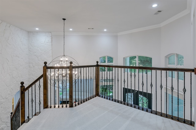 hall with carpet flooring, crown molding, and a chandelier