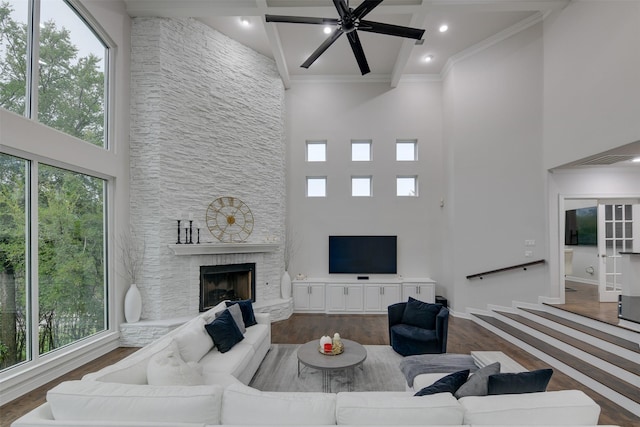 living area with dark wood-type flooring, a healthy amount of sunlight, a fireplace, and a ceiling fan