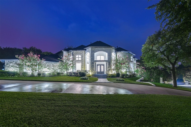 french provincial home with stone siding, french doors, and a front yard