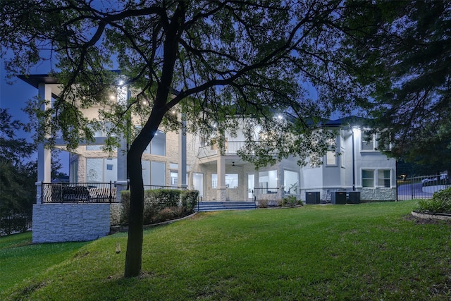 exterior space with central AC unit and a lawn