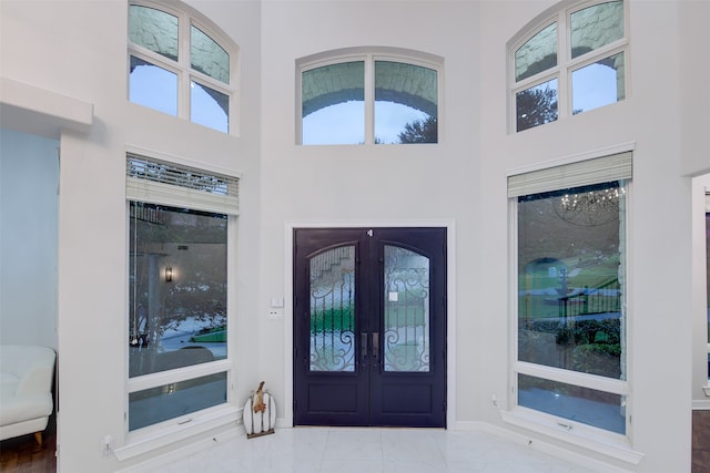 entrance foyer featuring a towering ceiling, tile patterned flooring, and french doors