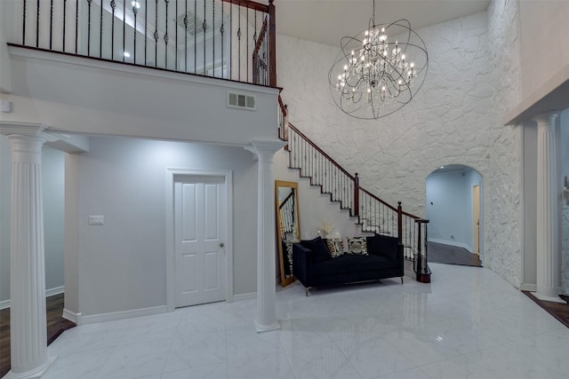 foyer entrance with marble finish floor, a high ceiling, stairway, and ornate columns