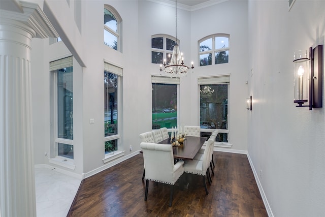 dining space featuring plenty of natural light, a notable chandelier, hardwood / wood-style flooring, and a towering ceiling