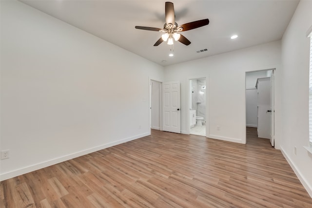 unfurnished bedroom with ceiling fan, a spacious closet, connected bathroom, and light hardwood / wood-style flooring