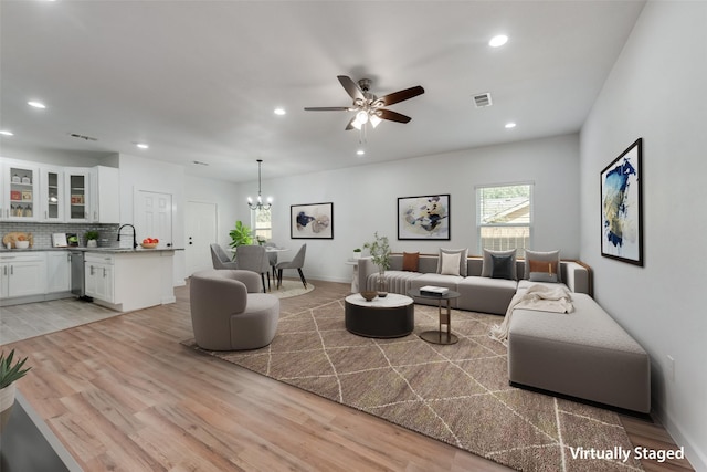 living room with sink, light hardwood / wood-style floors, and ceiling fan with notable chandelier