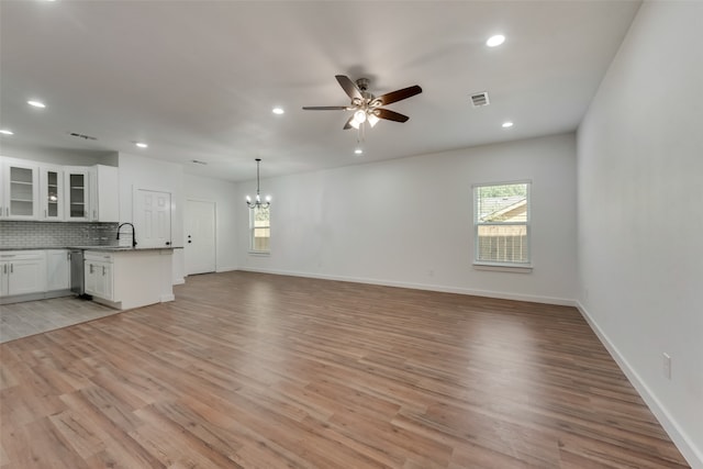 unfurnished living room featuring ceiling fan with notable chandelier, light hardwood / wood-style floors, and sink