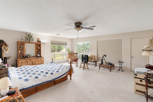 carpeted bedroom featuring ceiling fan and a textured ceiling