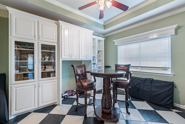 dining area featuring ceiling fan, a healthy amount of sunlight, light tile patterned floors, and a tray ceiling