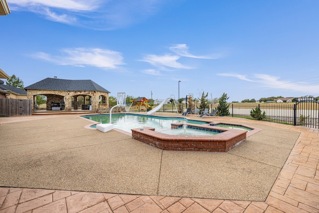 view of pool with a water slide, a patio area, an in ground hot tub, and a gazebo