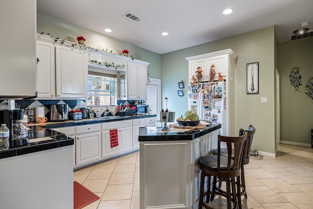 kitchen featuring white cabinetry, tasteful backsplash, a center island, and light tile patterned floors