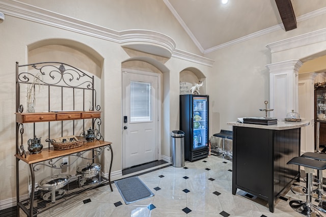 foyer featuring decorative columns, crown molding, vaulted ceiling, and light tile patterned floors