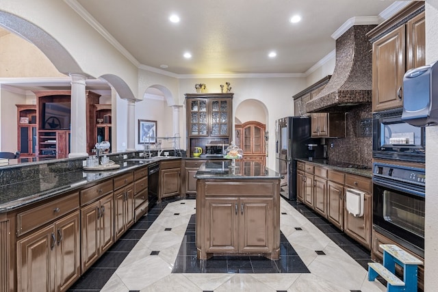 kitchen with dark stone counters, black appliances, tasteful backsplash, decorative columns, and a kitchen island