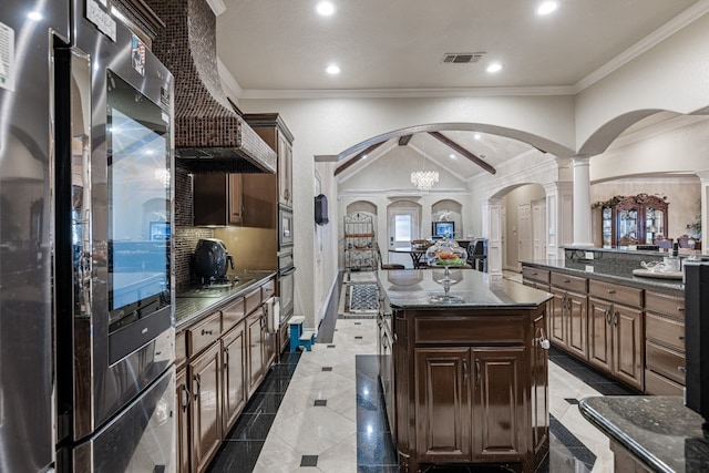 kitchen with light tile patterned flooring, decorative columns, dark stone counters, a center island, and lofted ceiling with beams