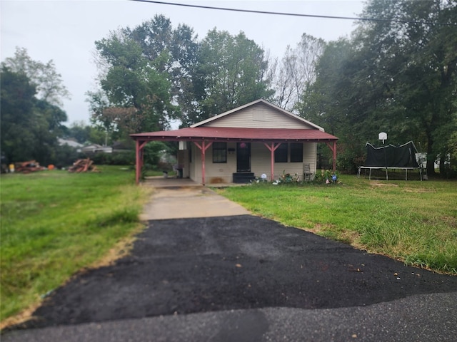 view of front of home featuring a front lawn, a trampoline, and a carport