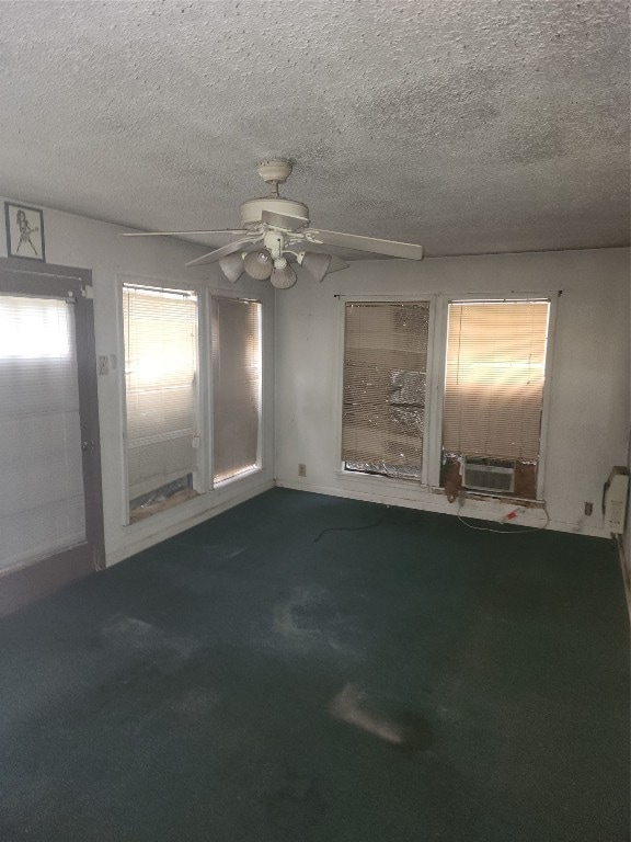 empty room with ceiling fan, dark colored carpet, and a textured ceiling