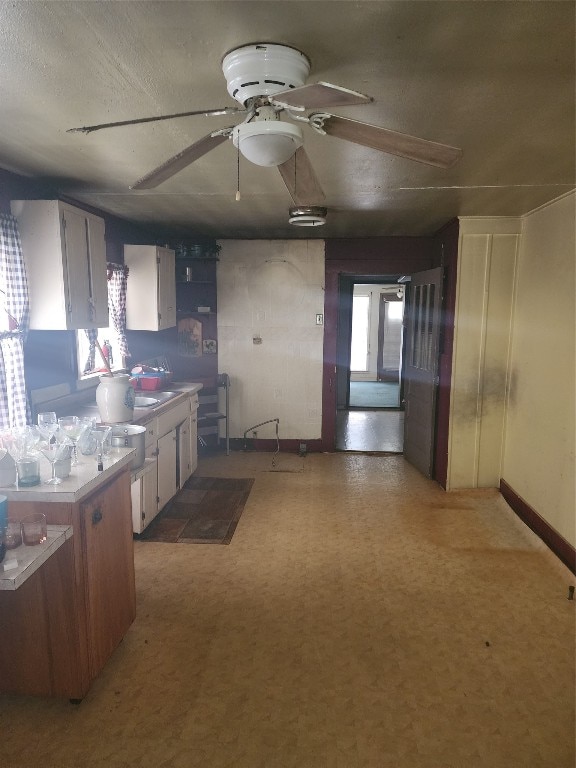 kitchen with ceiling fan and white cabinetry