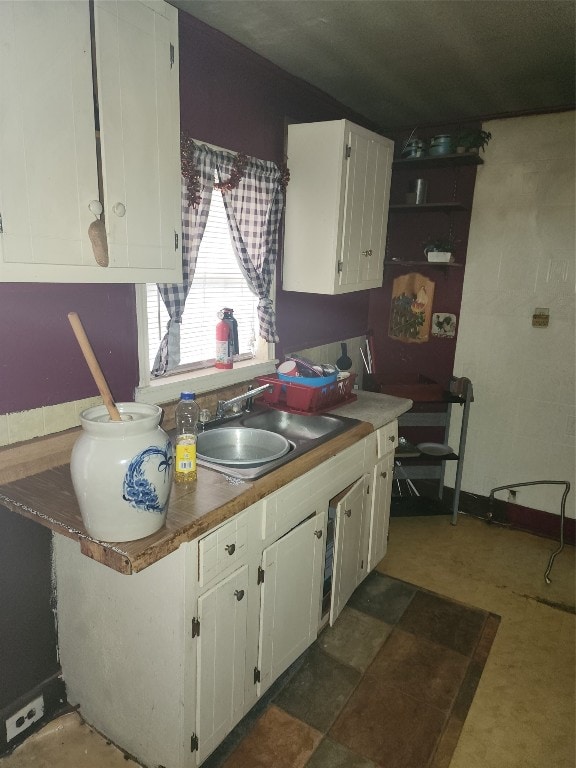 kitchen featuring sink, white cabinetry, and dark tile flooring