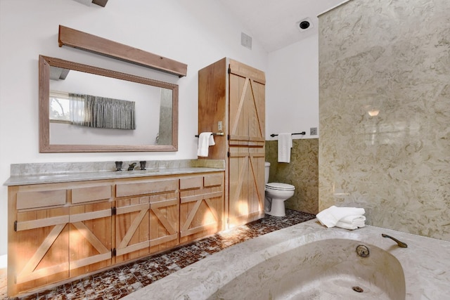 bathroom featuring toilet, a bath, vanity, and vaulted ceiling