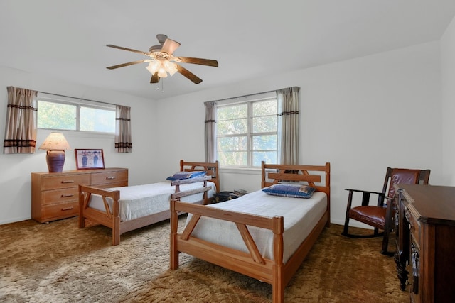 bedroom featuring dark carpet, multiple windows, and ceiling fan