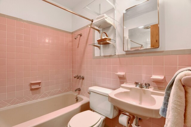 full bathroom with sink, tiled shower / bath combo, and tile walls