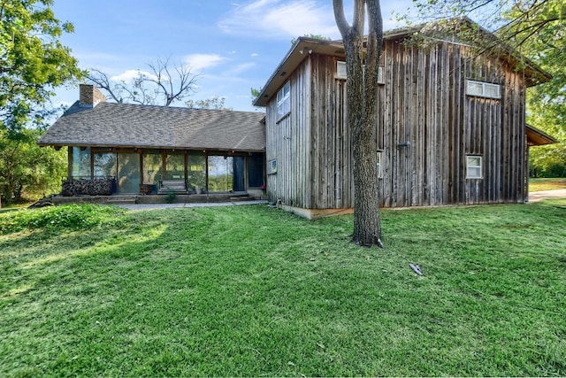 view of outbuilding featuring a sunroom and a lawn