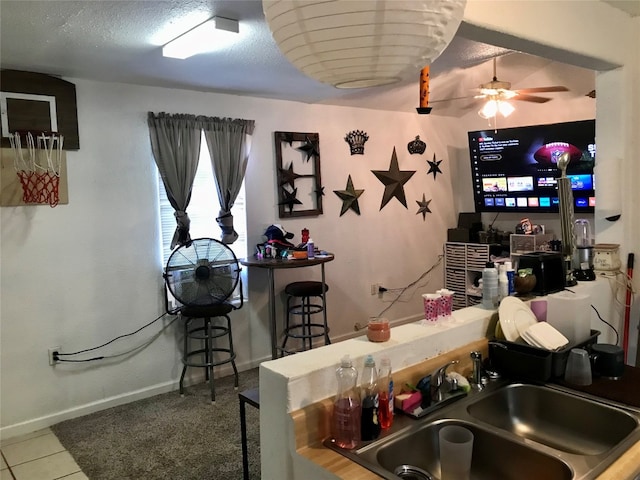 bar with ceiling fan, sink, light tile floors, and a textured ceiling