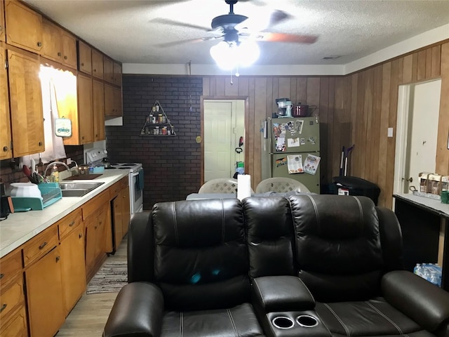 interior space with light hardwood / wood-style floors, stainless steel appliances, wooden walls, ceiling fan, and a textured ceiling