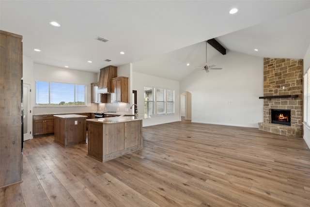 kitchen with kitchen peninsula, a healthy amount of sunlight, beam ceiling, and light wood-type flooring