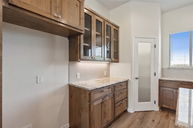 kitchen with light hardwood / wood-style floors, tasteful backsplash, and light stone counters