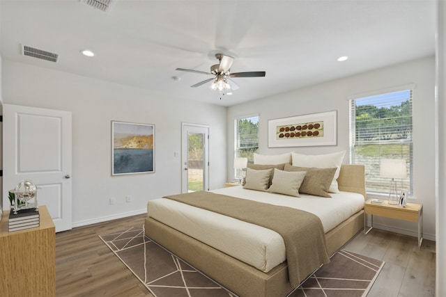 bedroom with access to outside, ceiling fan, wood-type flooring, and multiple windows