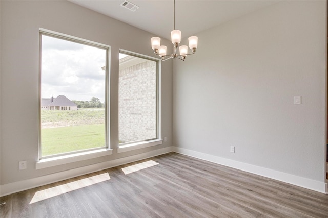 spare room featuring hardwood / wood-style flooring and a notable chandelier