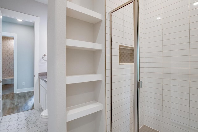 bathroom featuring an enclosed shower, vanity, toilet, and built in features