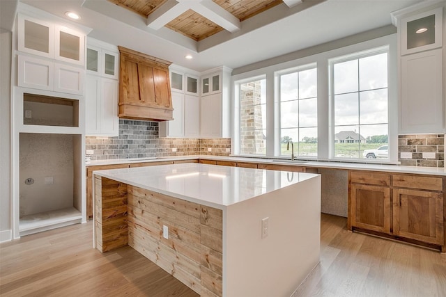 kitchen with beam ceiling, white cabinetry, a center island, sink, and coffered ceiling