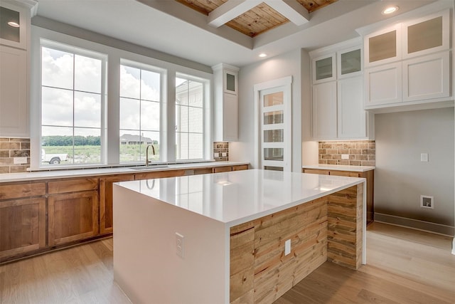 kitchen with white cabinets, a kitchen island, wood ceiling, and backsplash