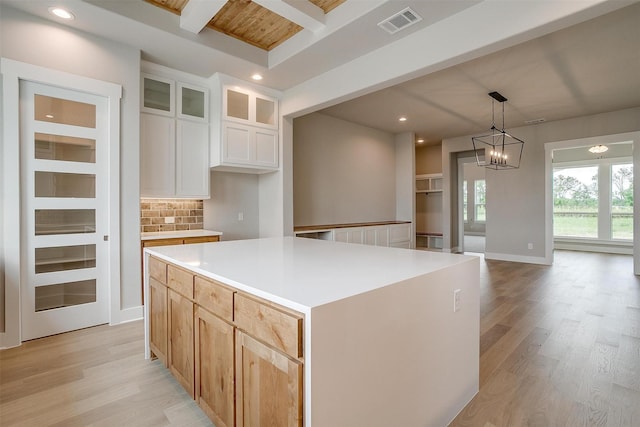 kitchen with white cabinets, decorative backsplash, decorative light fixtures, a kitchen island, and a chandelier