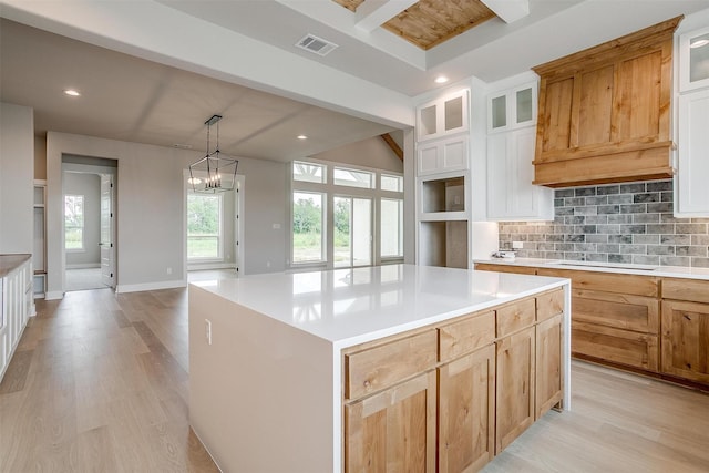 kitchen featuring white cabinets, a notable chandelier, a kitchen island, and backsplash