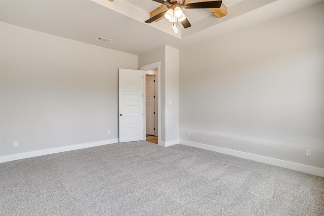 carpeted empty room with ceiling fan and a raised ceiling