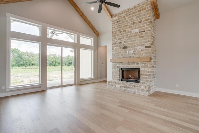 unfurnished living room featuring beamed ceiling, light wood-type flooring, high vaulted ceiling, and a stone fireplace