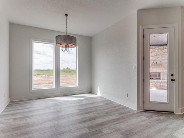 spare room with light wood-type flooring and an inviting chandelier