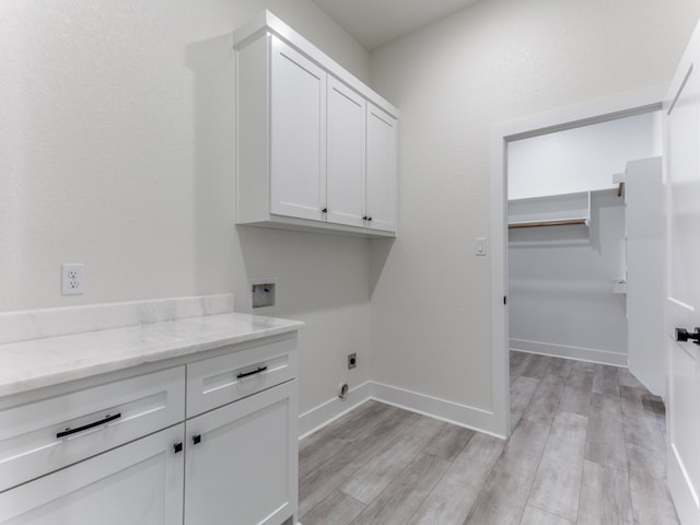 washroom with hookup for a washing machine, cabinets, hookup for an electric dryer, and light wood-type flooring